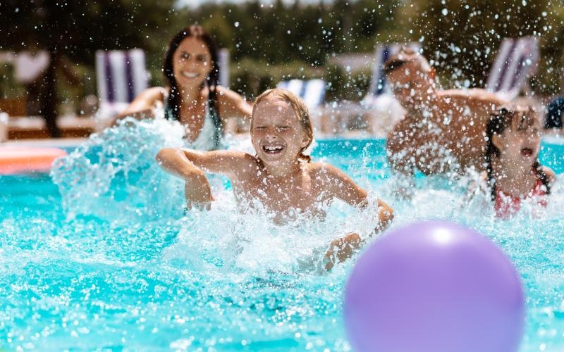 a group of people playing in a pool with a purple ball
